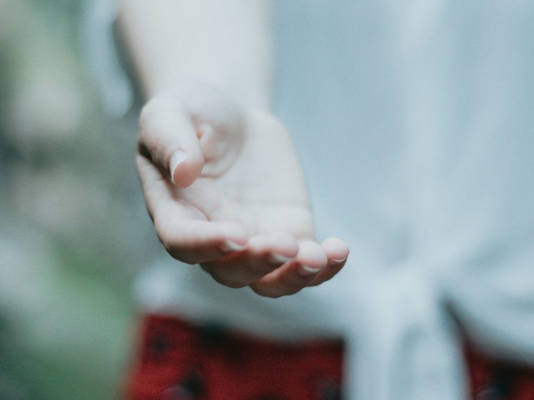 Offene Hand mit leicht gespreizten Fingern, in unscharfem Hintergrund.